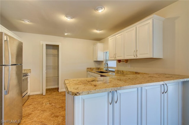 kitchen featuring appliances with stainless steel finishes, a sink, a peninsula, white cabinets, and baseboards