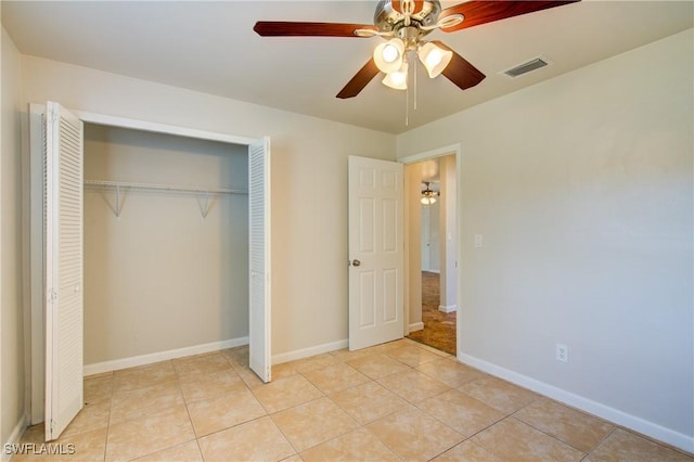unfurnished bedroom featuring a closet, light tile patterned floors, baseboards, and ceiling fan