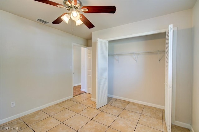 unfurnished bedroom featuring light tile patterned floors, a closet, ceiling fan, and baseboards
