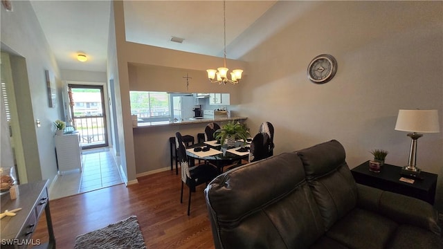 living area featuring a chandelier, wood finished floors, lofted ceiling, and baseboards