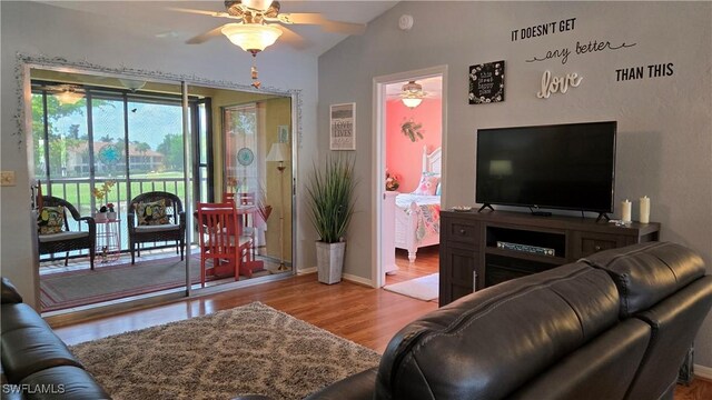 living room featuring a ceiling fan, wood finished floors, baseboards, and lofted ceiling