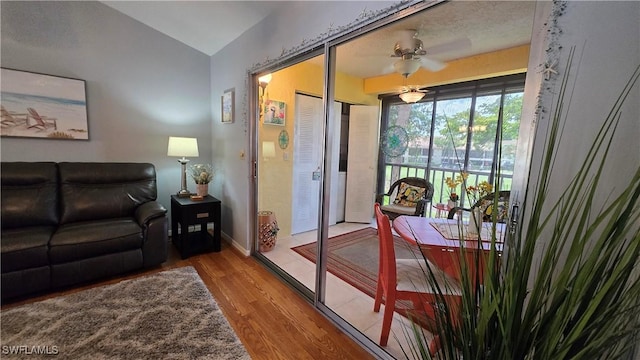 doorway to outside featuring wood finished floors, baseboards, a ceiling fan, and vaulted ceiling