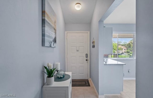 entryway with light tile patterned flooring and baseboards