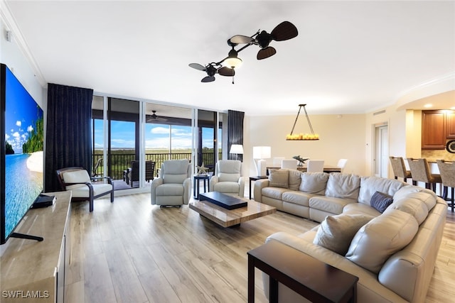living area featuring crown molding, a ceiling fan, light wood-style floors, and expansive windows