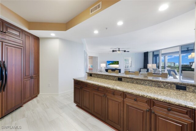 kitchen with open floor plan, recessed lighting, paneled built in refrigerator, light stone counters, and ceiling fan