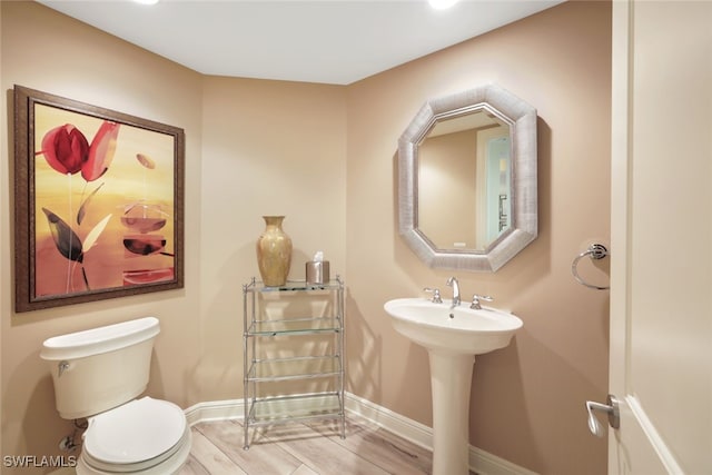 bathroom with baseboards, wood finished floors, and toilet