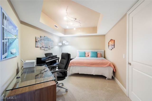 carpeted bedroom featuring a raised ceiling, baseboards, and a desk