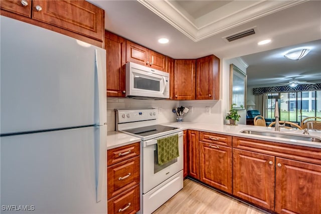 kitchen featuring white appliances, crown molding, a sink, brown cabinetry, and light countertops