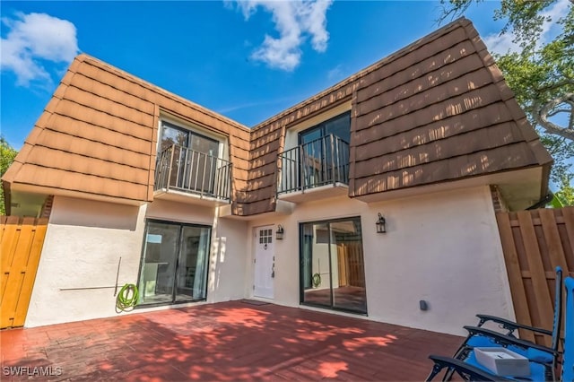 1428 Park Shore Cir Unit 2, Fort Myers, FL 33901 - rear view of house with stucco siding, a balcony, mansard roof, and fence
