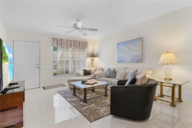 living room with a ceiling fan, baseboards, and light tile patterned flooring