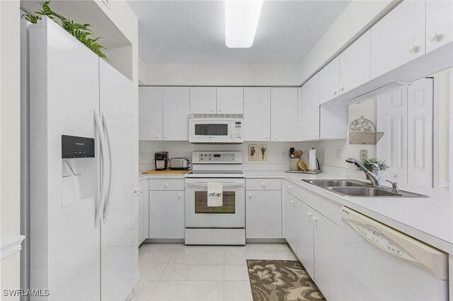 kitchen with white appliances, a sink, light countertops, white cabinets, and light marble finish flooring