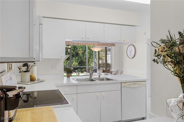 kitchen featuring white dishwasher, a sink, light countertops, and white cabinetry