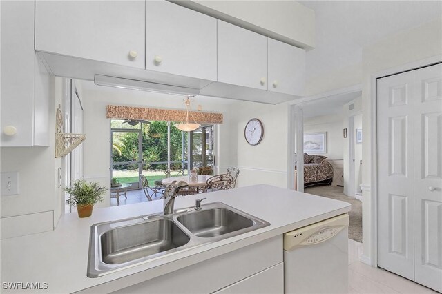 kitchen with white dishwasher, a sink, light countertops, and white cabinetry