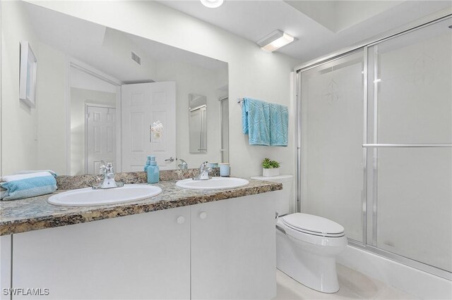 full bathroom with toilet, a stall shower, and double vanity