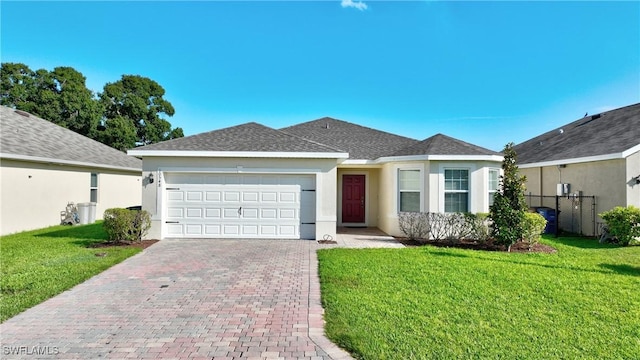ranch-style home featuring decorative driveway, an attached garage, stucco siding, a front yard, and roof with shingles