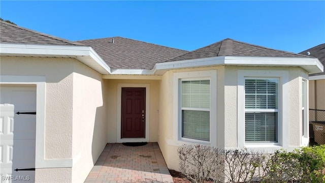 property entrance with stucco siding and roof with shingles