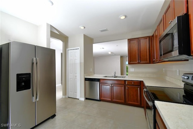 kitchen with stainless steel appliances, a sink, light countertops, light tile patterned floors, and recessed lighting