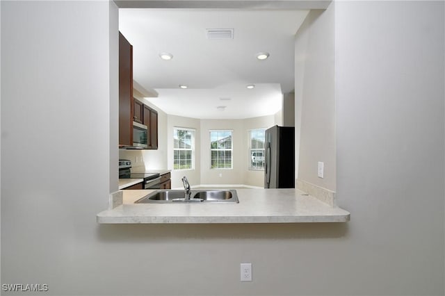 kitchen featuring stainless steel appliances, a sink, recessed lighting, light countertops, and a peninsula