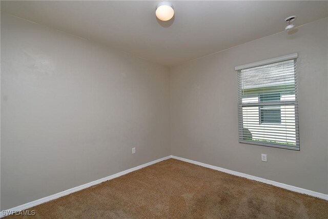 carpeted empty room featuring baseboards