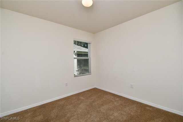 spare room featuring carpet floors and baseboards