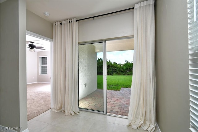 doorway to outside with tile patterned floors, ceiling fan, and carpet flooring