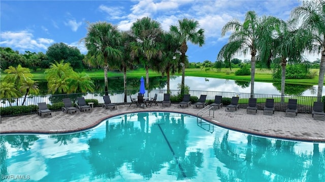 community pool featuring fence, a patio, and a water view