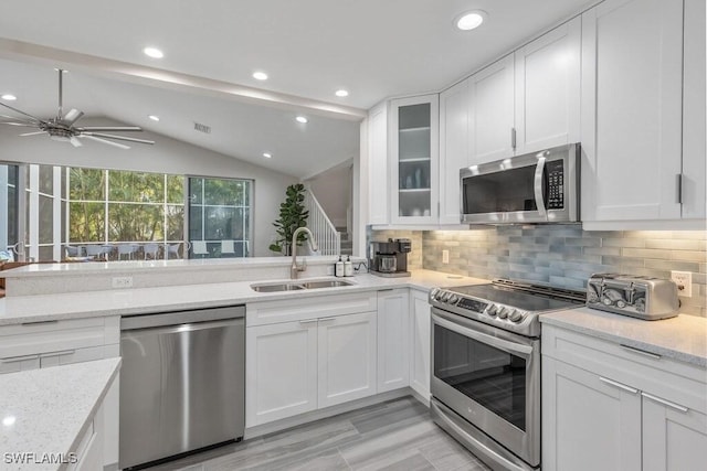 kitchen featuring appliances with stainless steel finishes, a sink, lofted ceiling, white cabinets, and ceiling fan