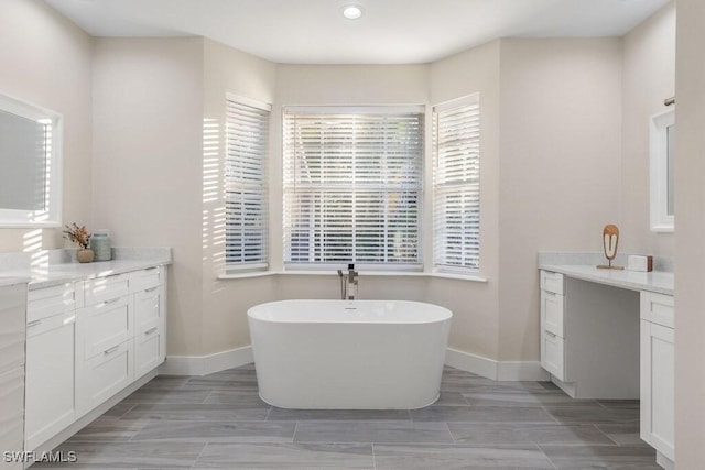 full bath with baseboards, a soaking tub, vanity, wood finish floors, and recessed lighting