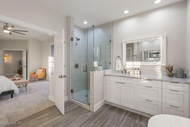 ensuite bathroom featuring a shower stall, wood finish floors, ceiling fan, vanity, and recessed lighting