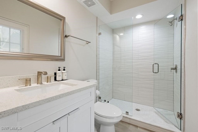 full bathroom featuring toilet, a stall shower, vanity, and recessed lighting