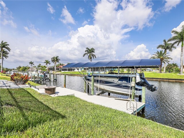 dock featuring boat lift, a water view, and a yard
