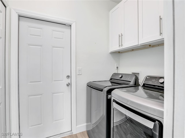 clothes washing area with independent washer and dryer, cabinet space, baseboards, and light wood finished floors