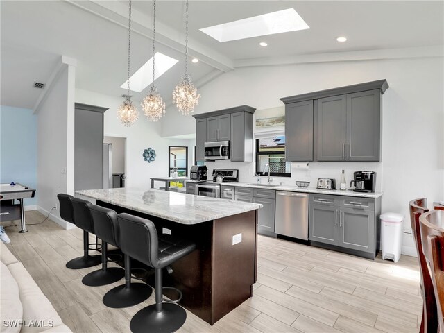 kitchen with appliances with stainless steel finishes, a skylight, gray cabinetry, and a center island
