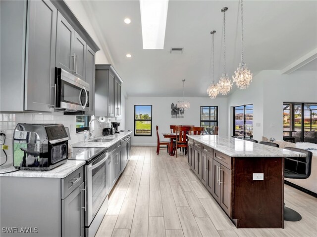 kitchen featuring stainless steel appliances, a chandelier, gray cabinetry, a kitchen island, and recessed lighting