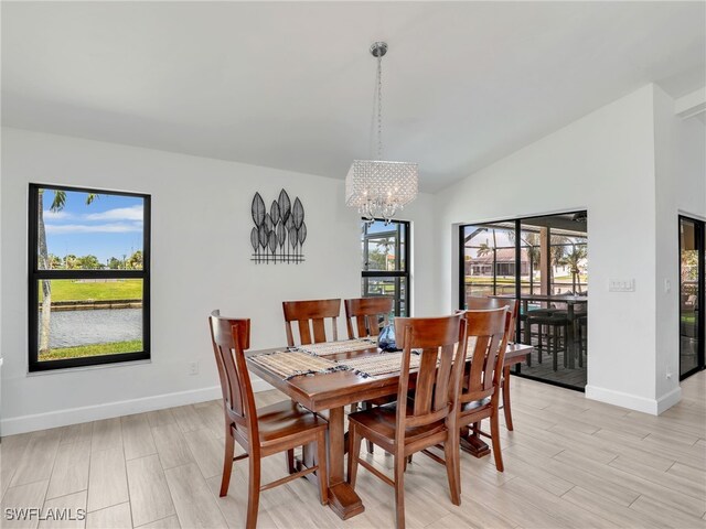 dining room featuring lofted ceiling, a chandelier, baseboards, and light wood-type flooring