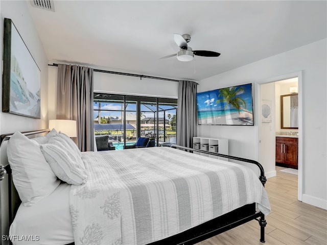 bedroom featuring wood finished floors, baseboards, ceiling fan, ensuite bath, and a sink