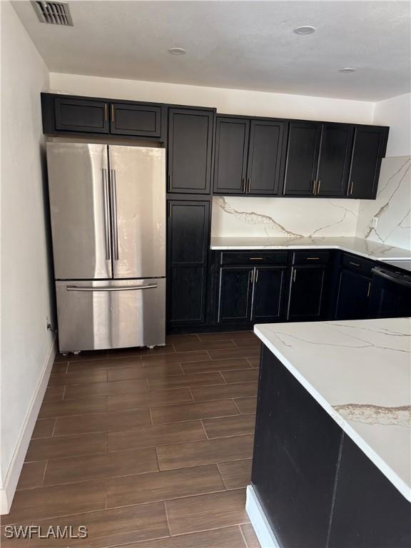 6321 Royal Woods Dr, Fort Myers, FL 33908 - kitchen with freestanding refrigerator, dark cabinets, wood tiled floors, baseboards, and decorative backsplash