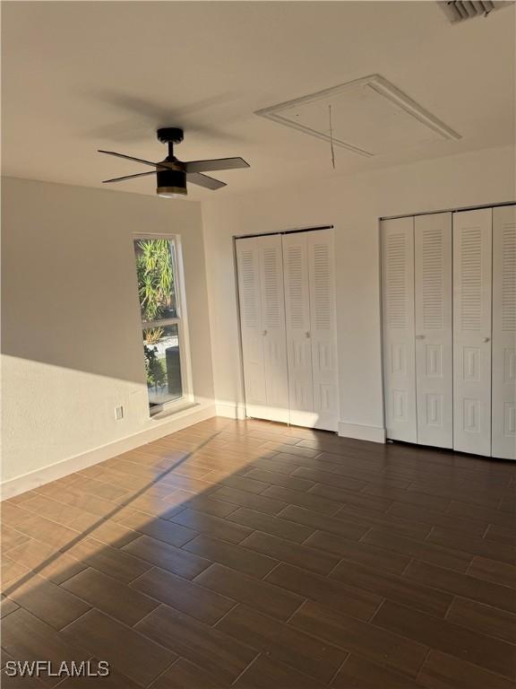6321 Royal Woods Dr, Fort Myers, FL 33908 - unfurnished bedroom with attic access, dark wood-type flooring, multiple closets, and ceiling fan