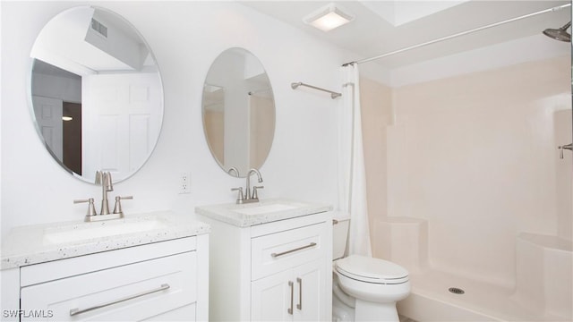 full bathroom featuring a stall shower, two vanities, and toilet