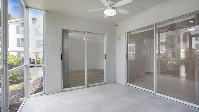 unfurnished sunroom featuring a ceiling fan and plenty of natural light