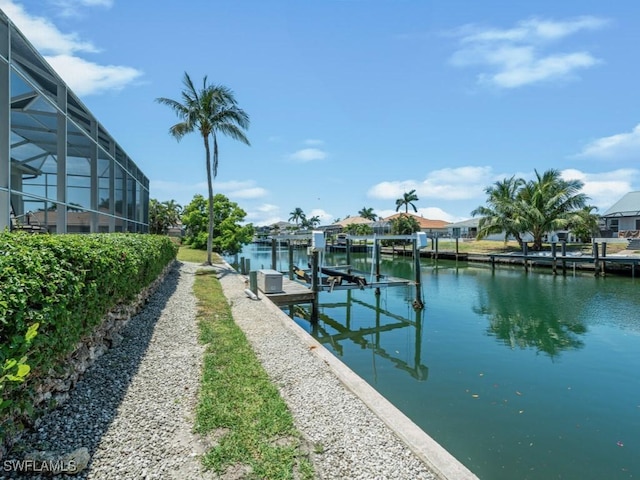 dock area with boat lift, a water view, and a lanai