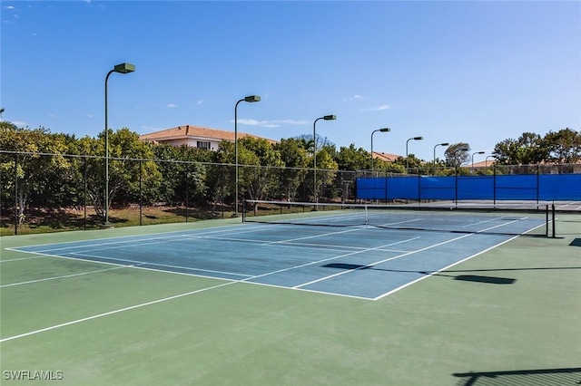view of tennis court featuring community basketball court and fence