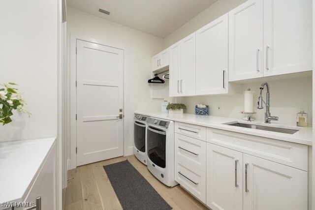 6145 Sea Grass Ln, Naples, FL 34116 - clothes washing area featuring washer and clothes dryer, cabinet space, and light wood-style floors
