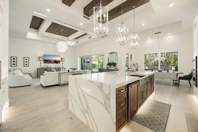 6145 Sea Grass Ln, Naples, FL 34116 - kitchen featuring a chandelier, open floor plan, a high ceiling, beamed ceiling, and light wood-type flooring