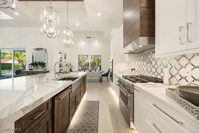 6145 Sea Grass Ln, Naples, FL 34116 - kitchen featuring stainless steel appliances, a sink, wall chimney range hood, a chandelier, and decorative backsplash