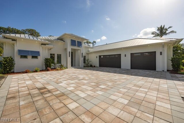6145 Sea Grass Ln, Naples, FL 34116 - view of front facade featuring decorative driveway, a garage, a standing seam roof, and metal roof