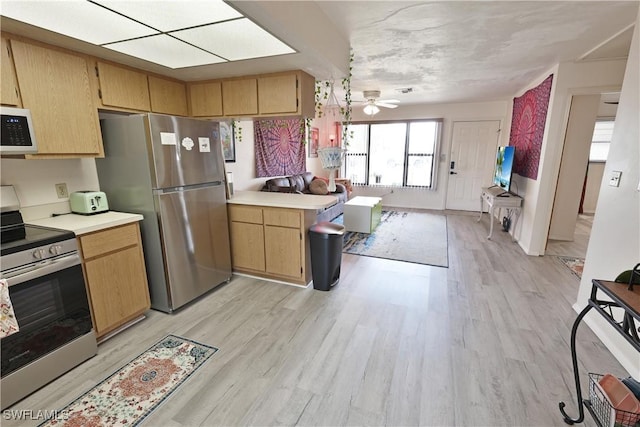 kitchen with stainless steel appliances, open floor plan, light wood-style flooring, and light countertops