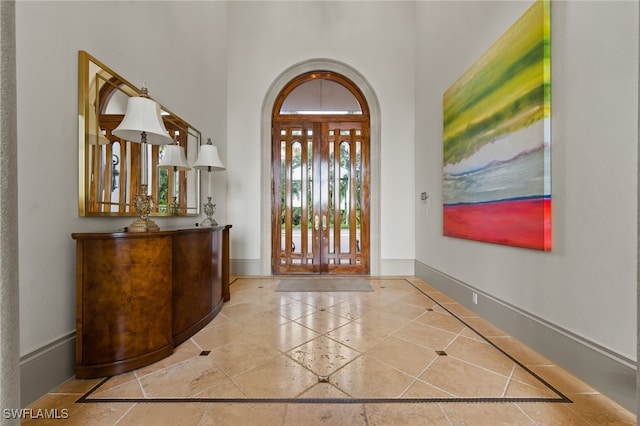 6387 Highcroft Dr, Naples, FL 34119 - entrance foyer featuring inlaid floor details, a towering ceiling, baseboards, and tile patterned floors
