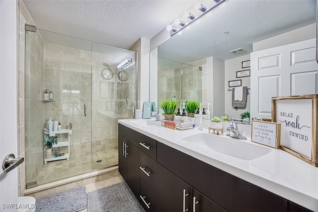 13160 Bella Casa Cir Unit 2115, Fort Myers, FL 33966 - bathroom with a stall shower, double vanity, and a textured ceiling