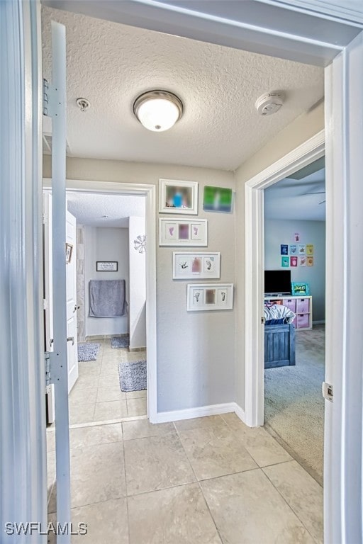 13160 Bella Casa Cir Unit 2115, Fort Myers, FL 33966 - corridor featuring light tile patterned flooring, a textured ceiling, and baseboards
